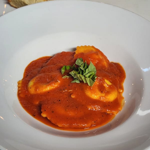 Finas Trattoria's ravioli pasta dish, covered in red sauce and garnished with fresh basil.