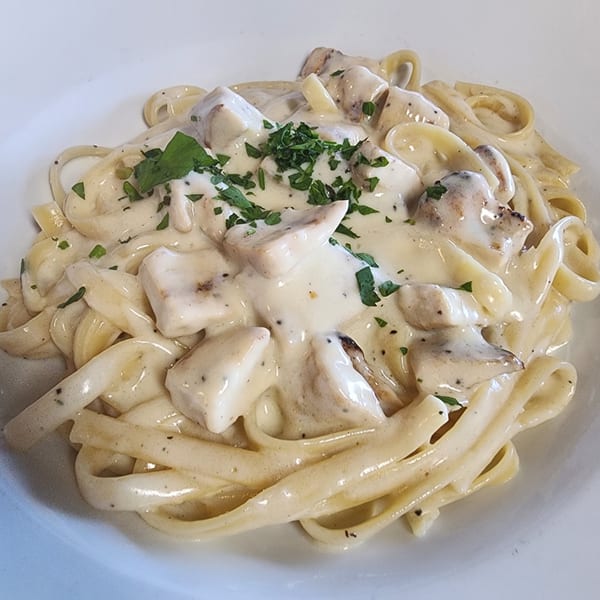Creamy fettuccine pasta with chicken and mushrooms, garnished with fresh parsley.
