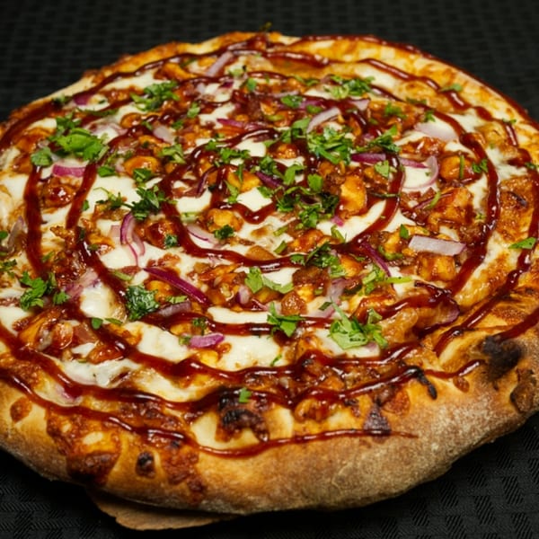 Finas Trattoria's BBQ chicken pizza, topped with red onions, cilantro, and a BBQ sauce drizzle.